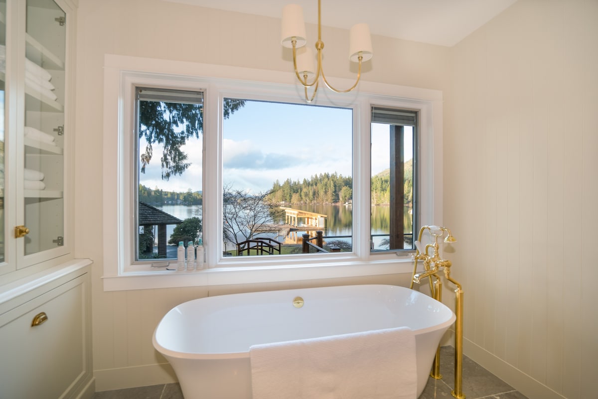 Freestanding soaker tub with brass fixtures and lake views