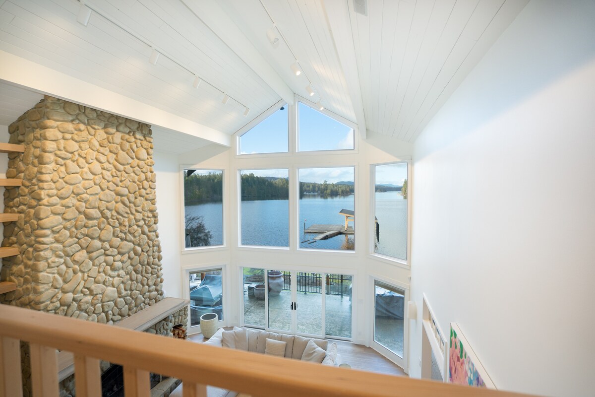 Mezzanine view of great room with stone chimney and lake beyond
