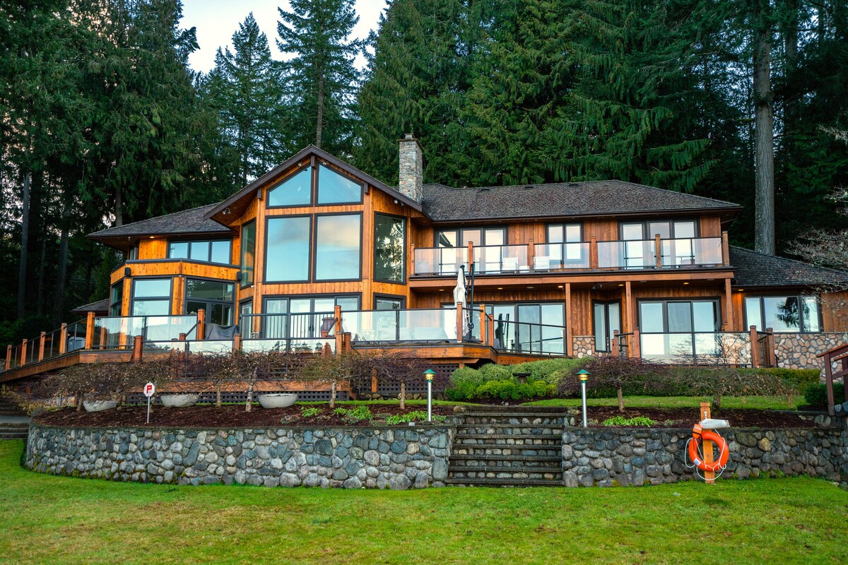 Main house exterior from lawn showing glass windows and deck
