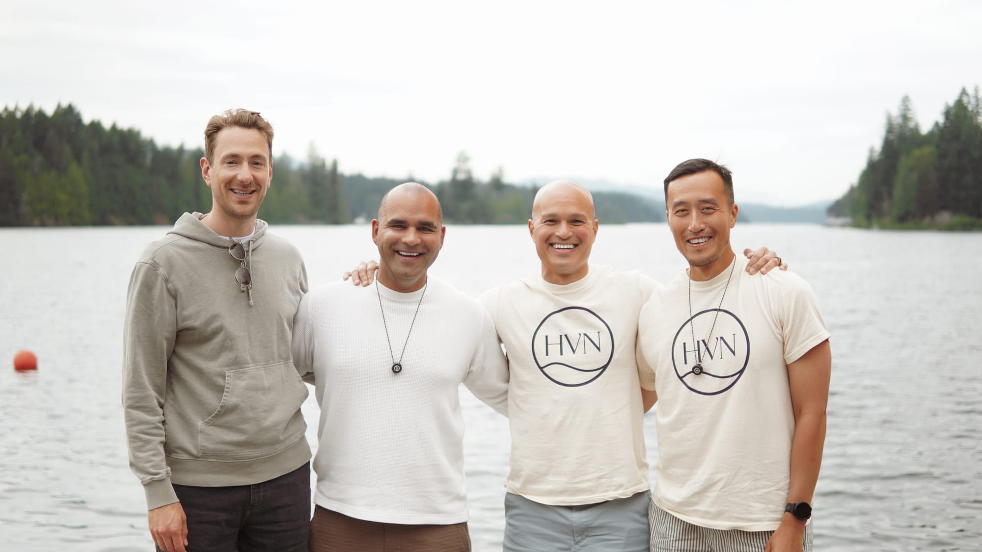 Four colleagues on the dock at golden hour, lake stretching behind them