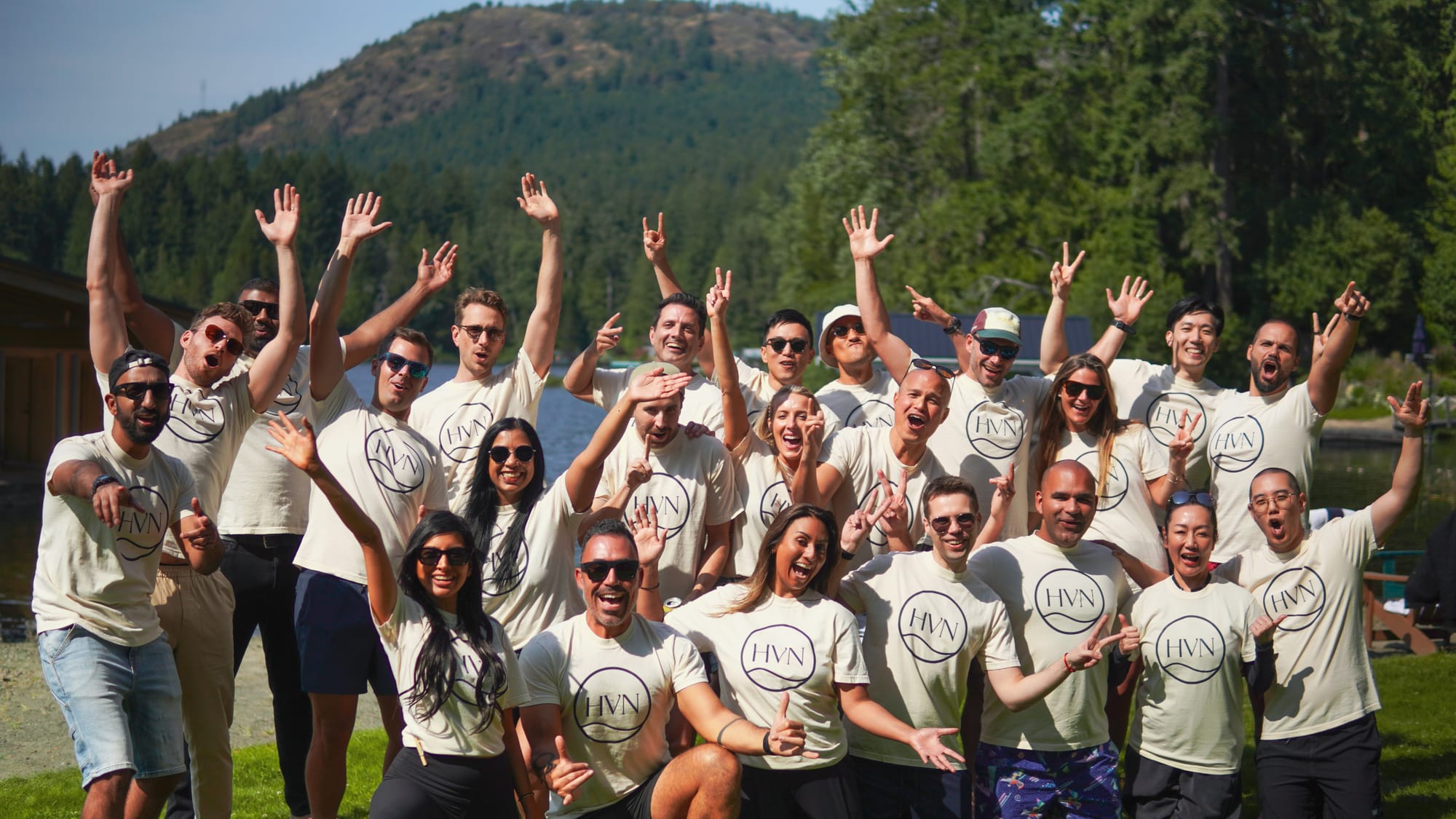 Corporate retreat group celebrating on the lawn with the lake behind them